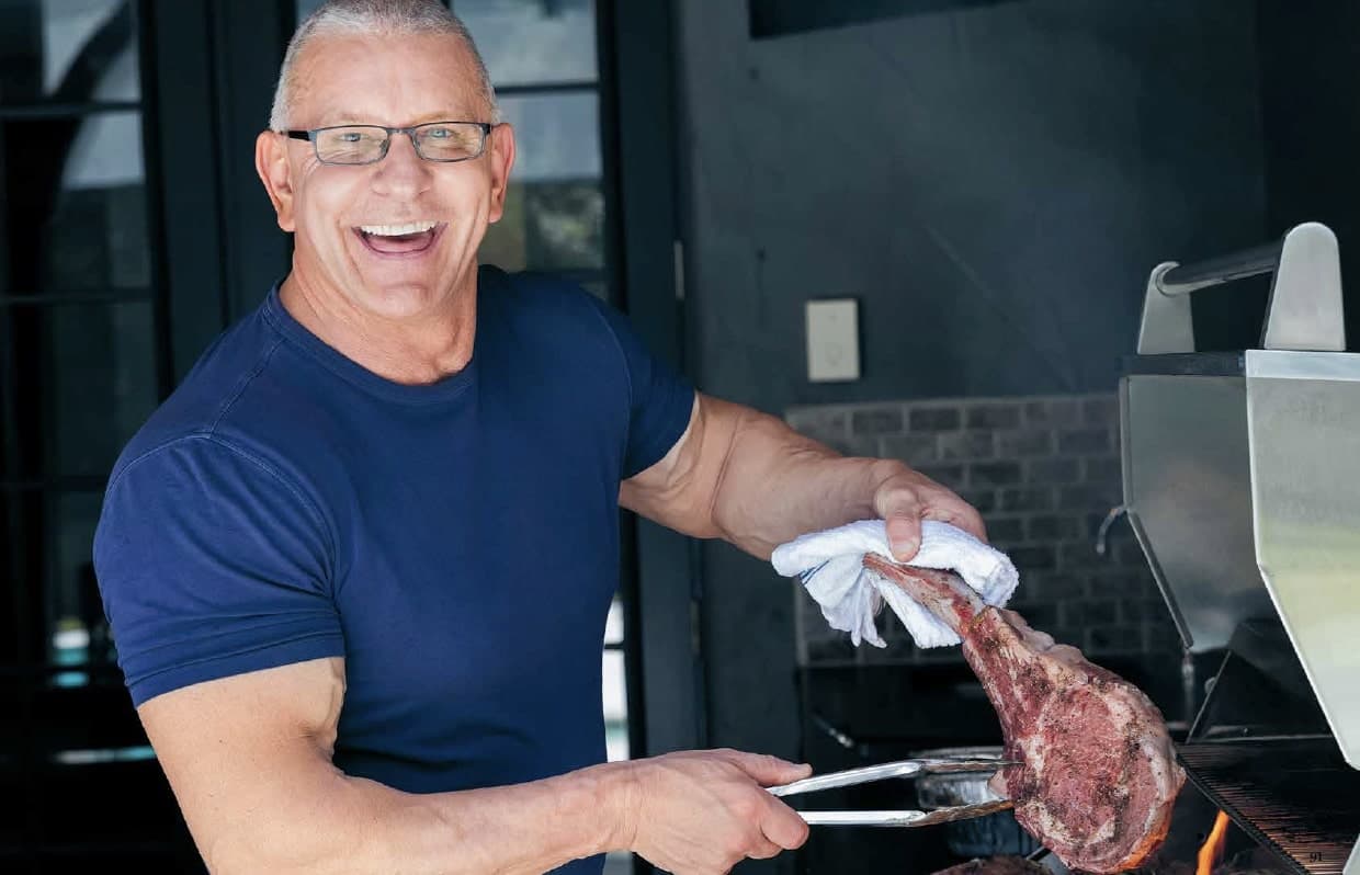 Robert Irvine holding grilled coffee rubbed cowboy ribeye